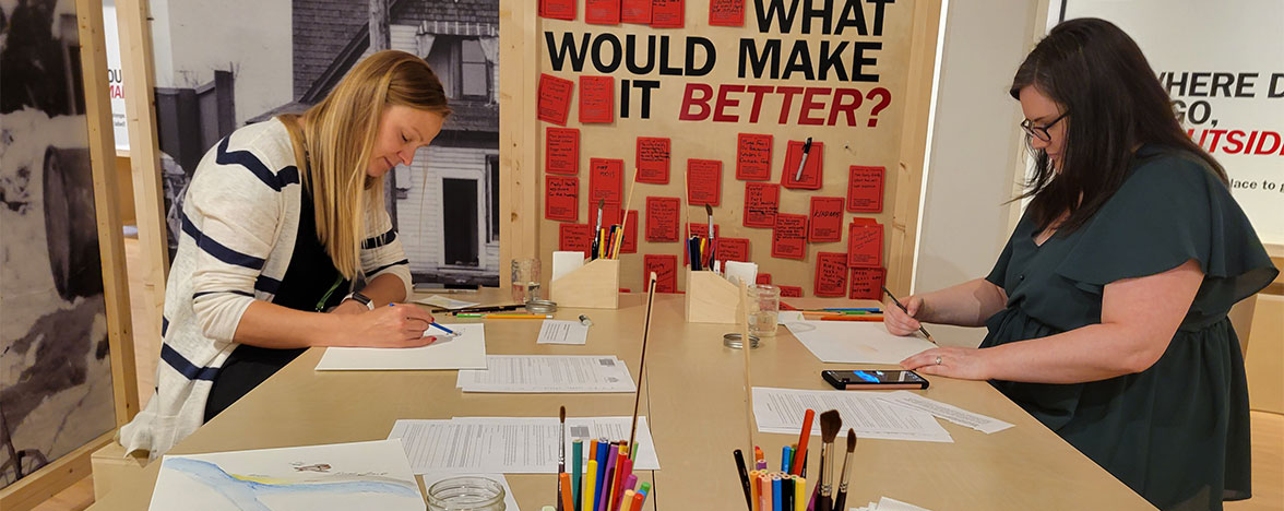 Two females at a desk with art supplies