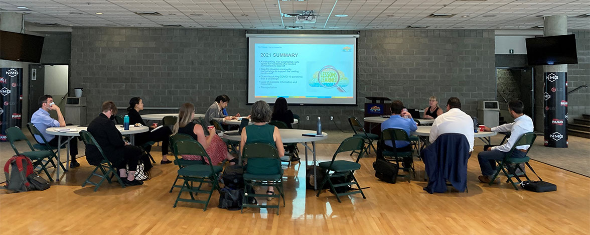 Round tables of individuals faces a presentation screen