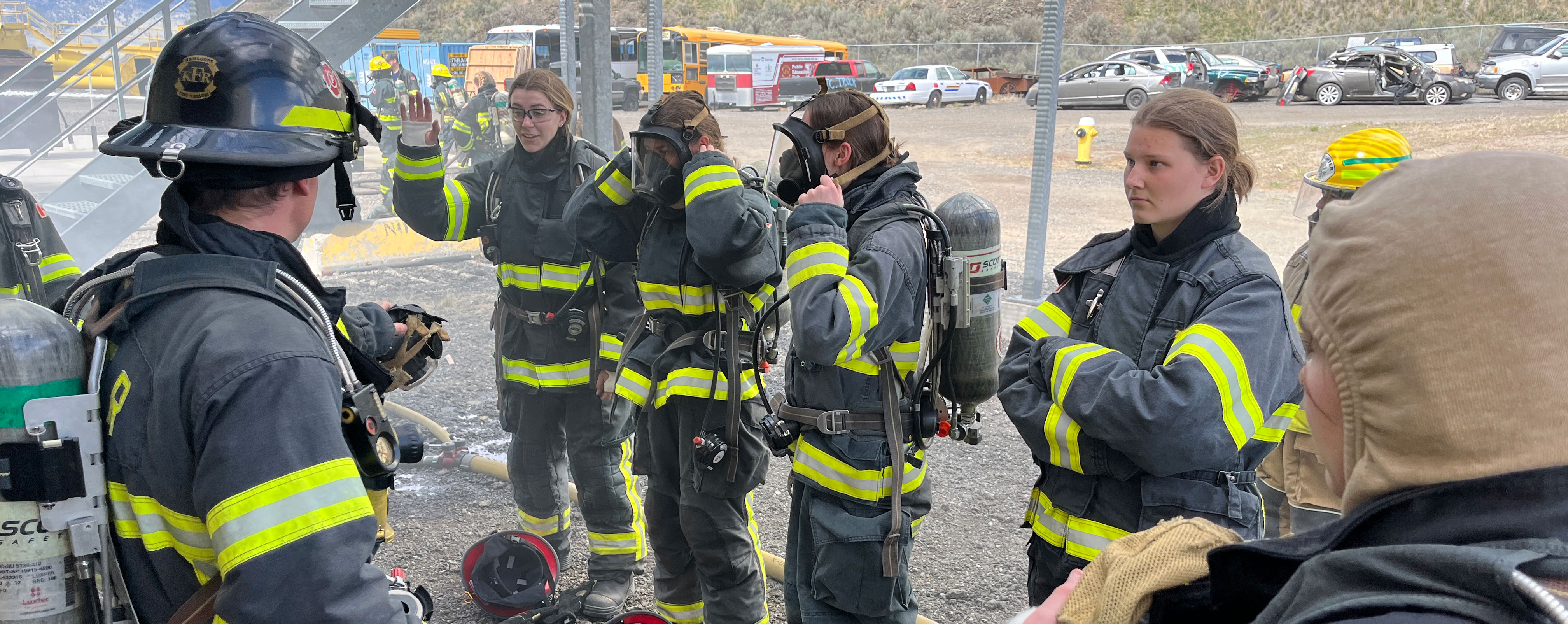 female students in firefighter gear listening to instructions