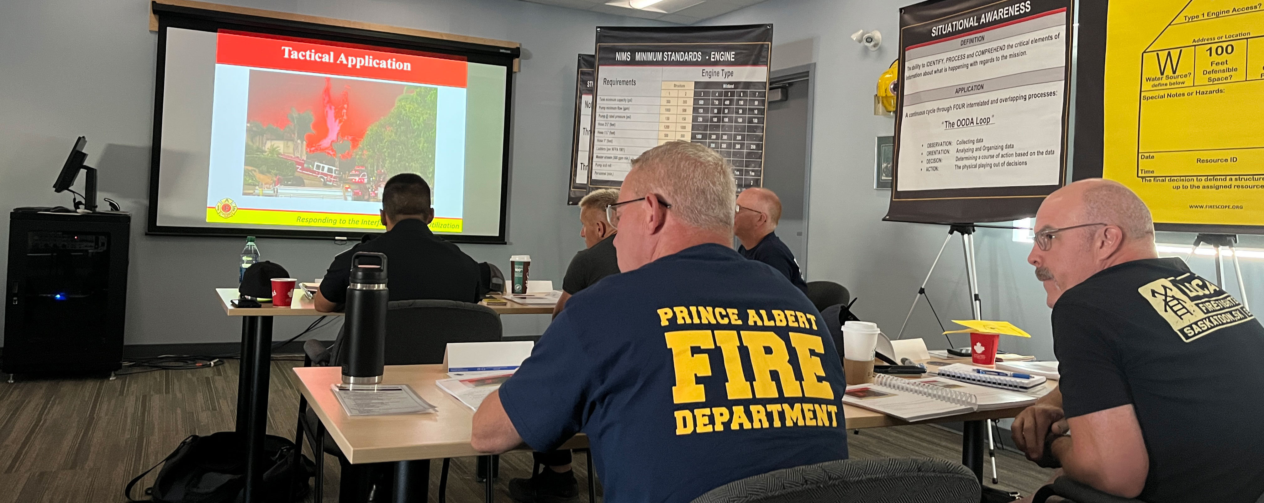 A classroom of firefighters looking at a image on the wall providing a training exercise