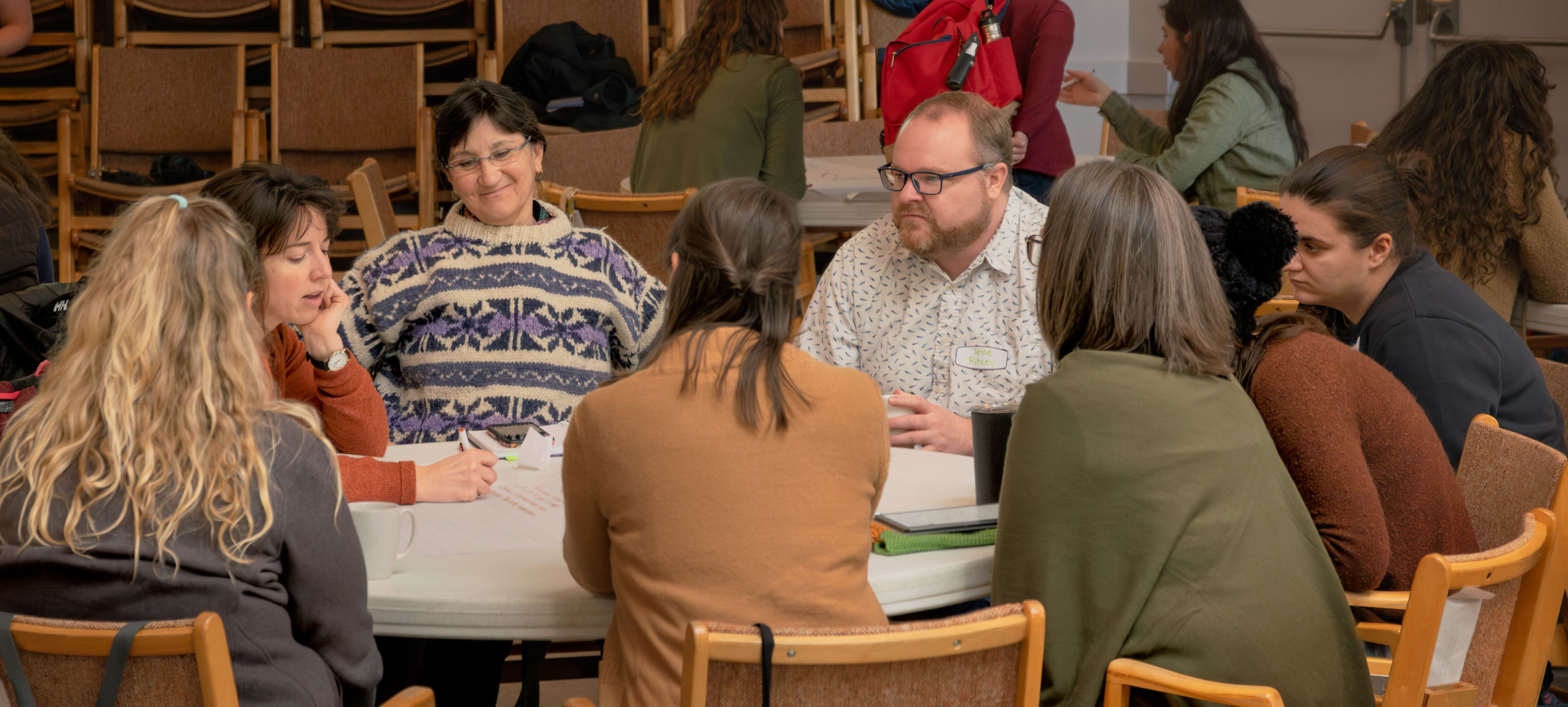eight adults conversing at a round table