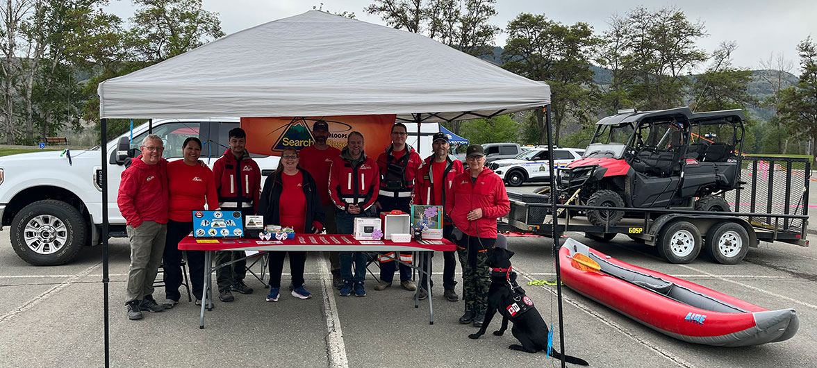 search and rescue volunteers in red jackets under canopy tent