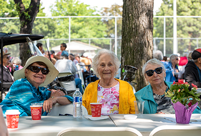 three smiling seniors enjoying lunch at the seniors picnic