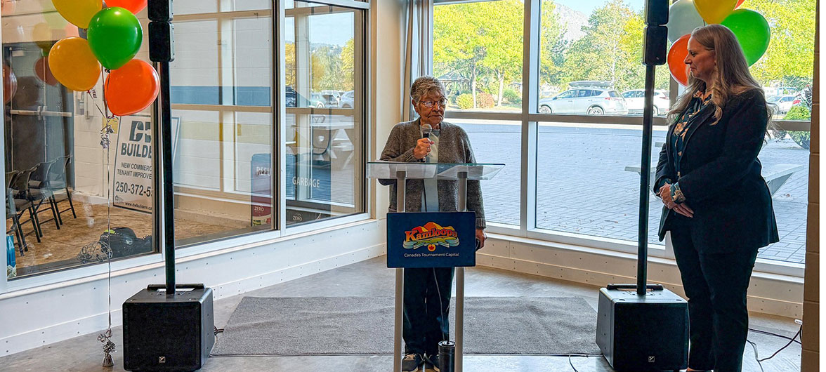 Elder in a gray blazer speaking behind a podium
