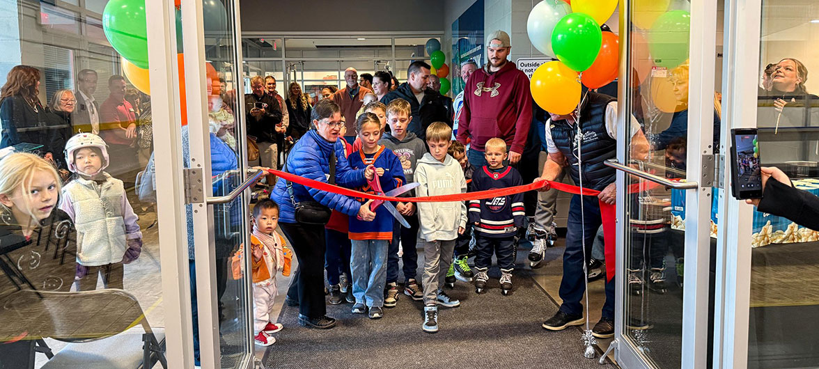 red ribbon being cut with excited children