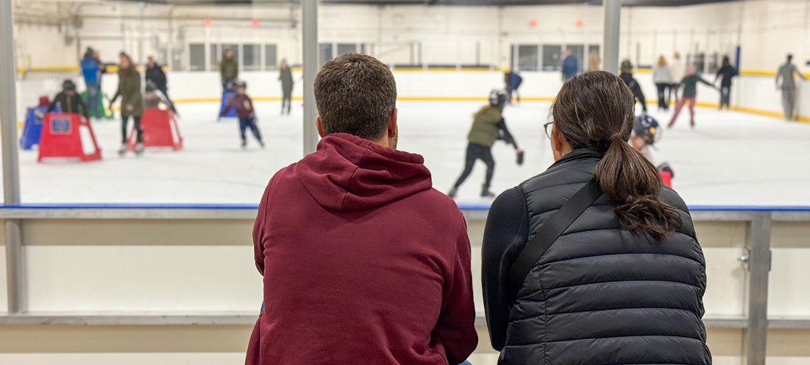 two adults watching skating