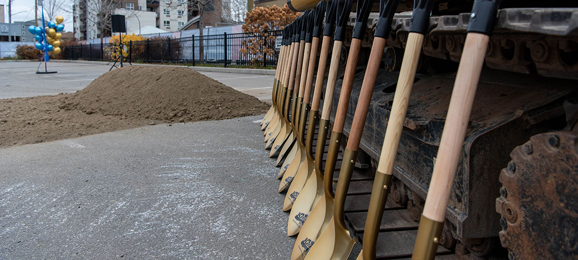 dirt pile with gold shovels lined up next to it