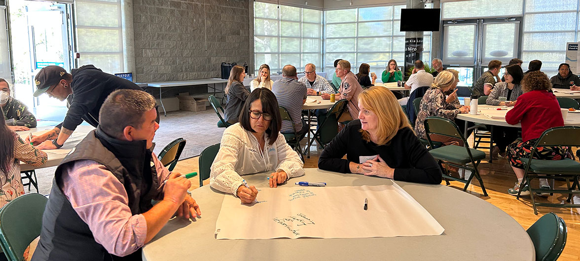 three people at a table with paper and pens