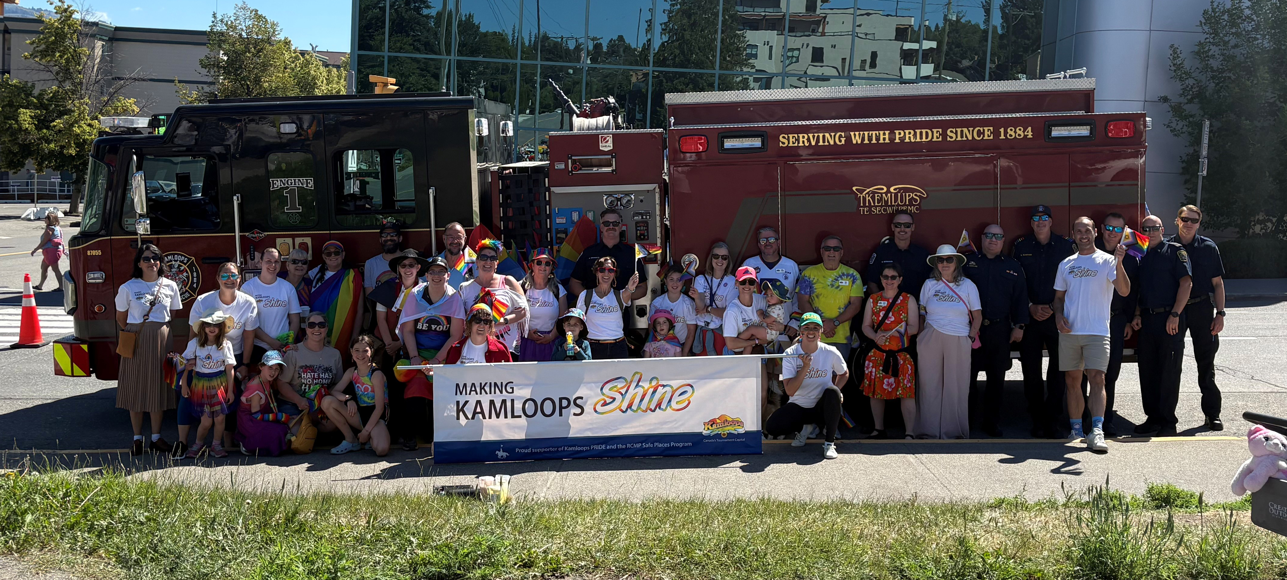 Crowd of City staff standing in front of a fire truck with a pride parade banner