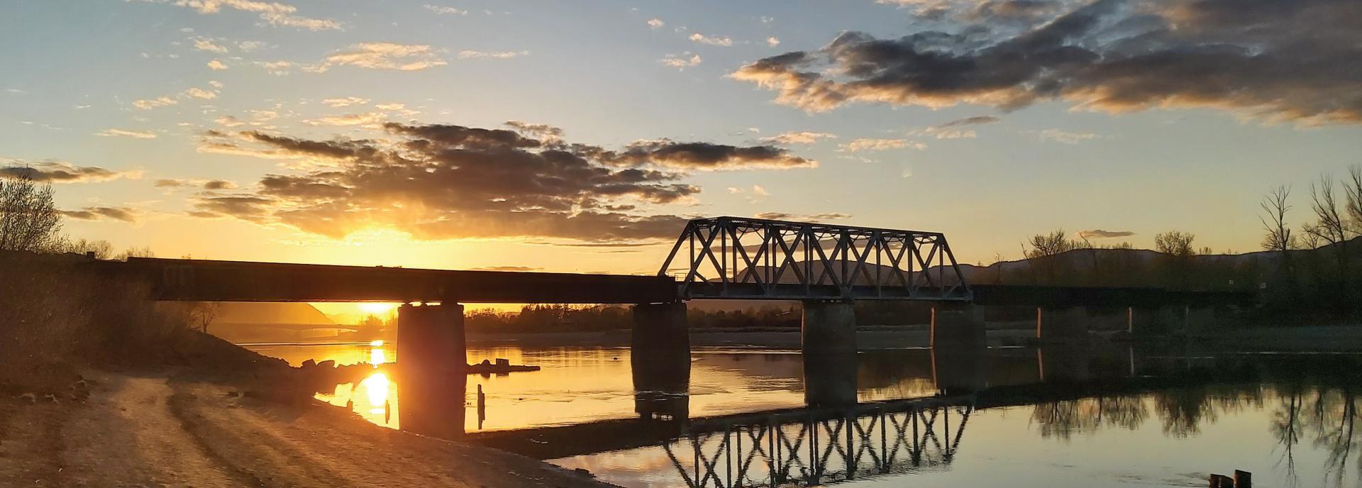 Sunset over river with train bridge