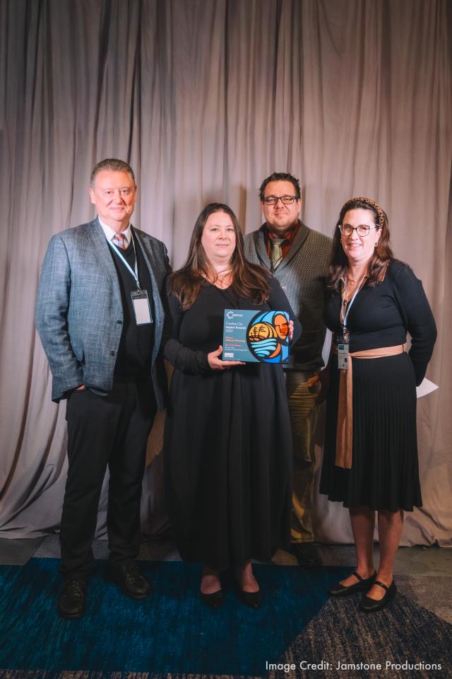 four people showing an award