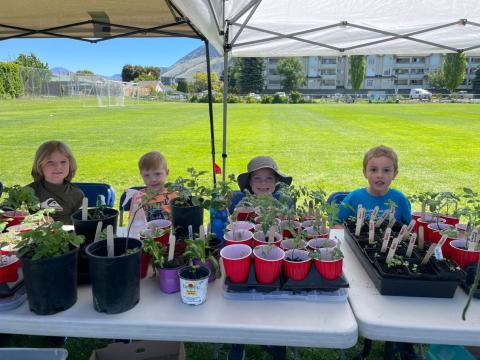Kids sitting in a booth with plants in posts in front of them