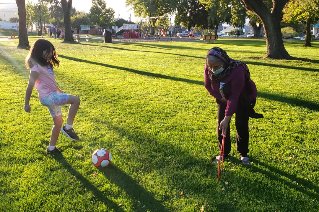 Two individuals kicking a ball in a park setting
