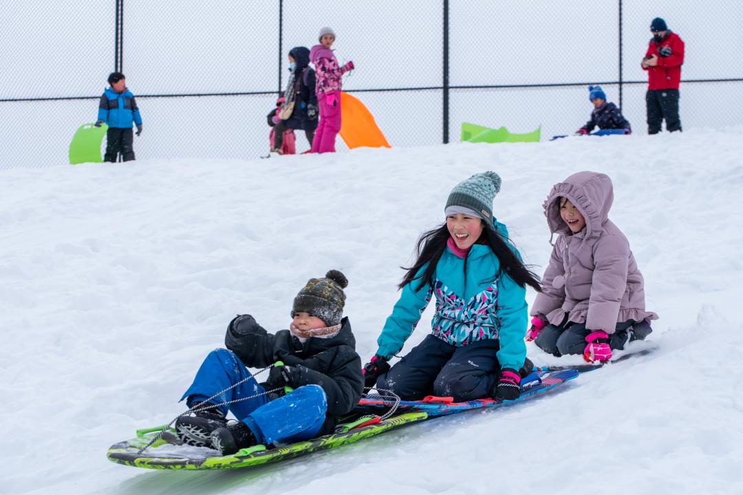 Kids sledding in winter down a hill
