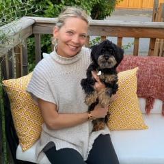 blonde women in light sweater holding black and tan dog