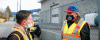 Two males in hi-vis vests and masks conversing 