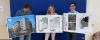Three individuals holding up architectural drawings of a new home building development