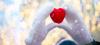 white mittens holding a red felt heart