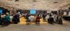 guests in room around tables in front of presentation screen