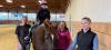 four females and a brown horse in a riding arena