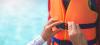adult securing buckle on orange lifejacket 